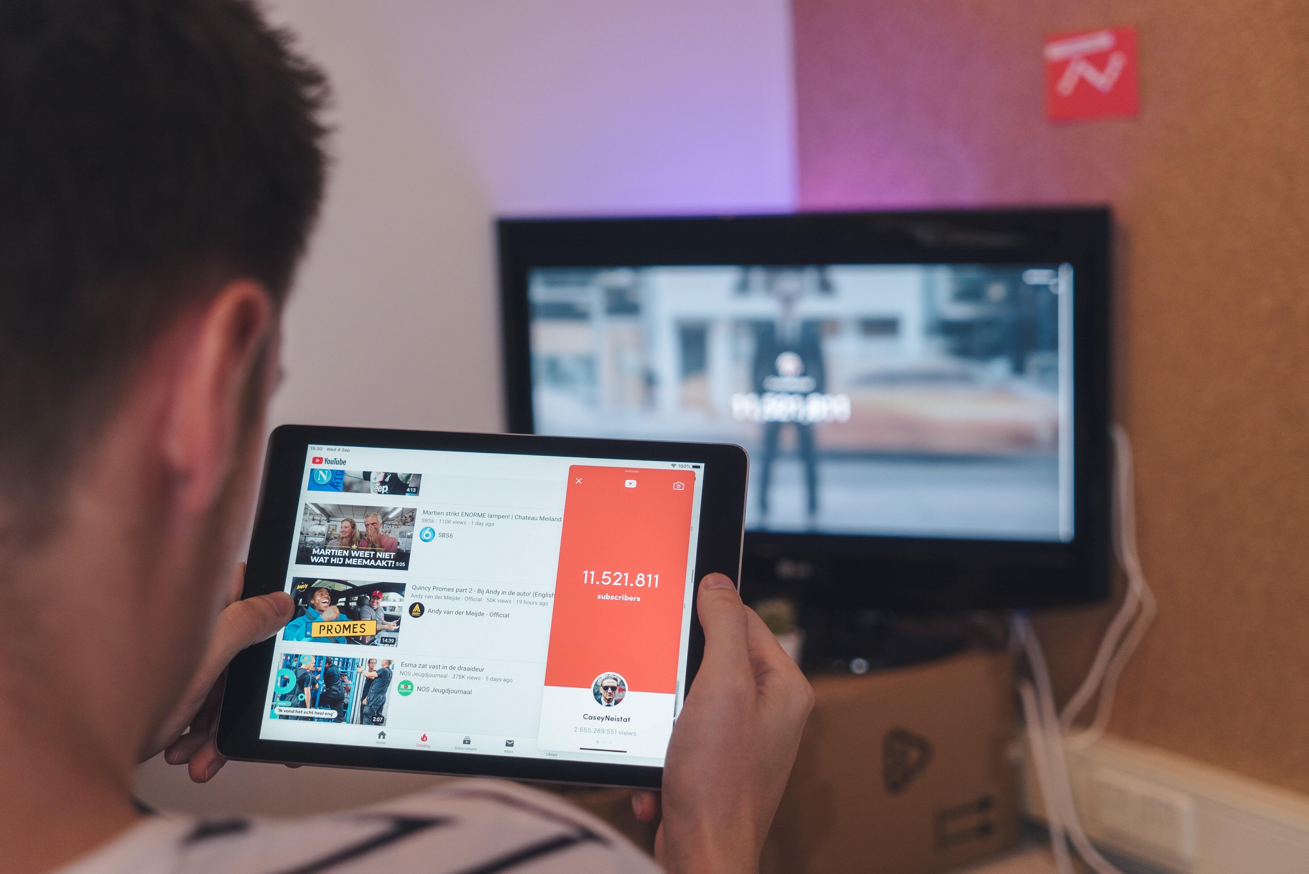Man watching YouTube on tablet while watching TV