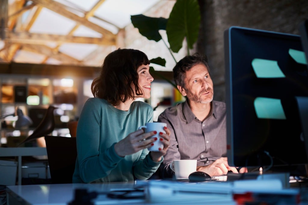 Man and woman smiling at computer screen in office