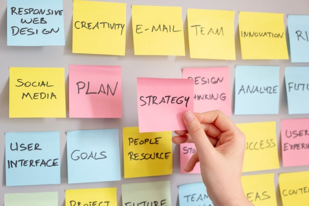 hand putting strategy sticky note on marketing plan