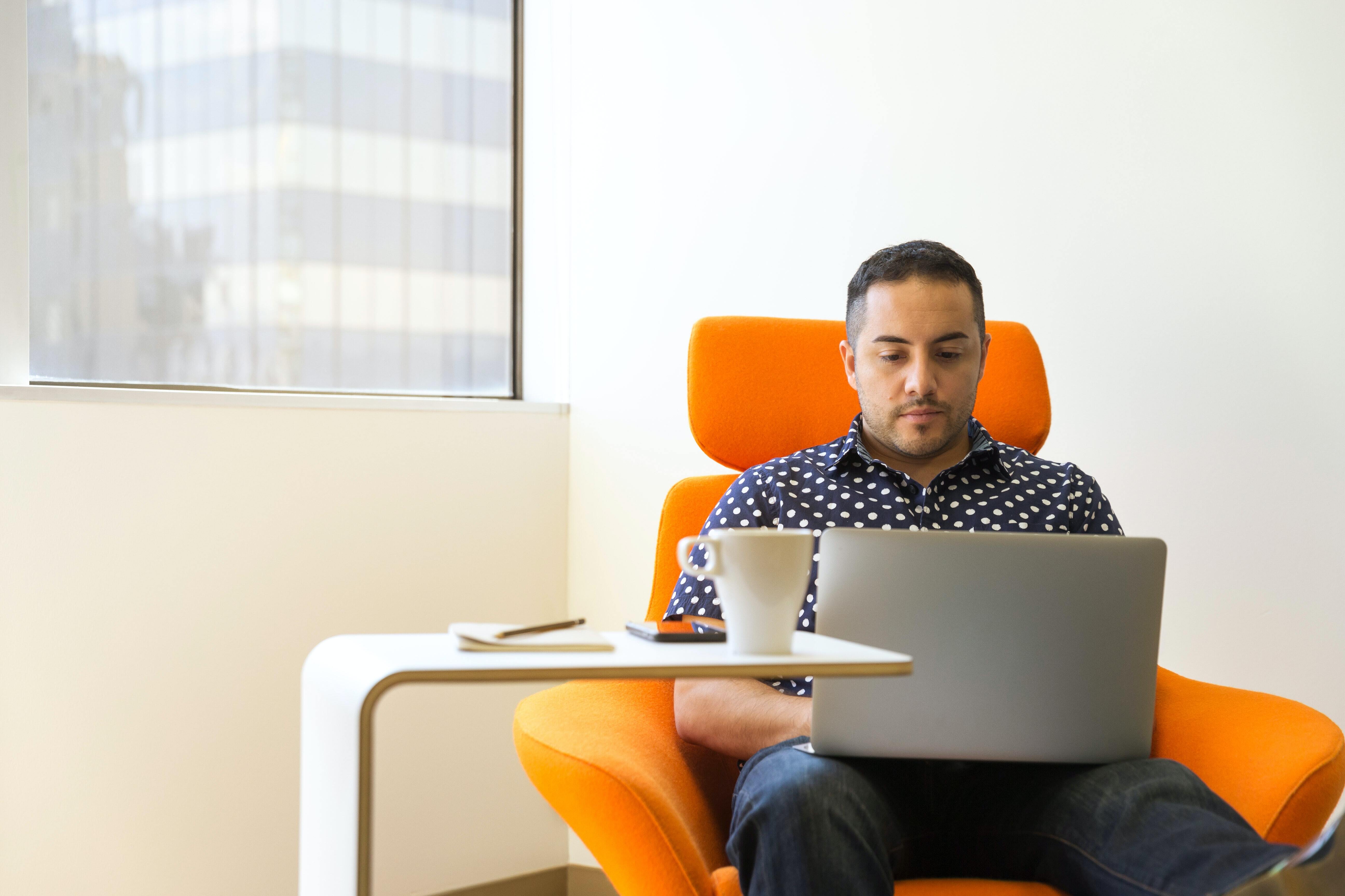 man sat at chair using laptop