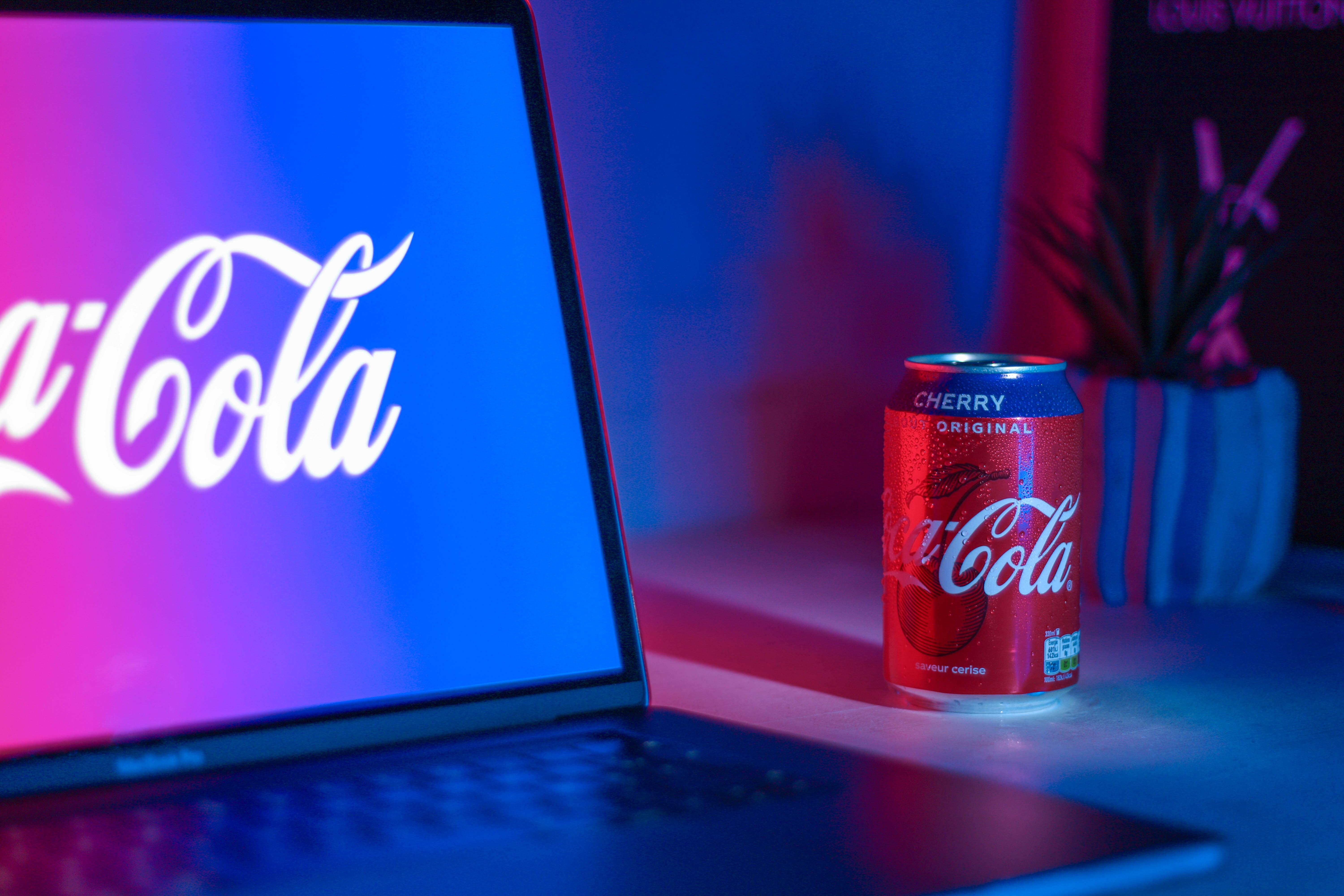 Coca Cola branding on laptop next to can