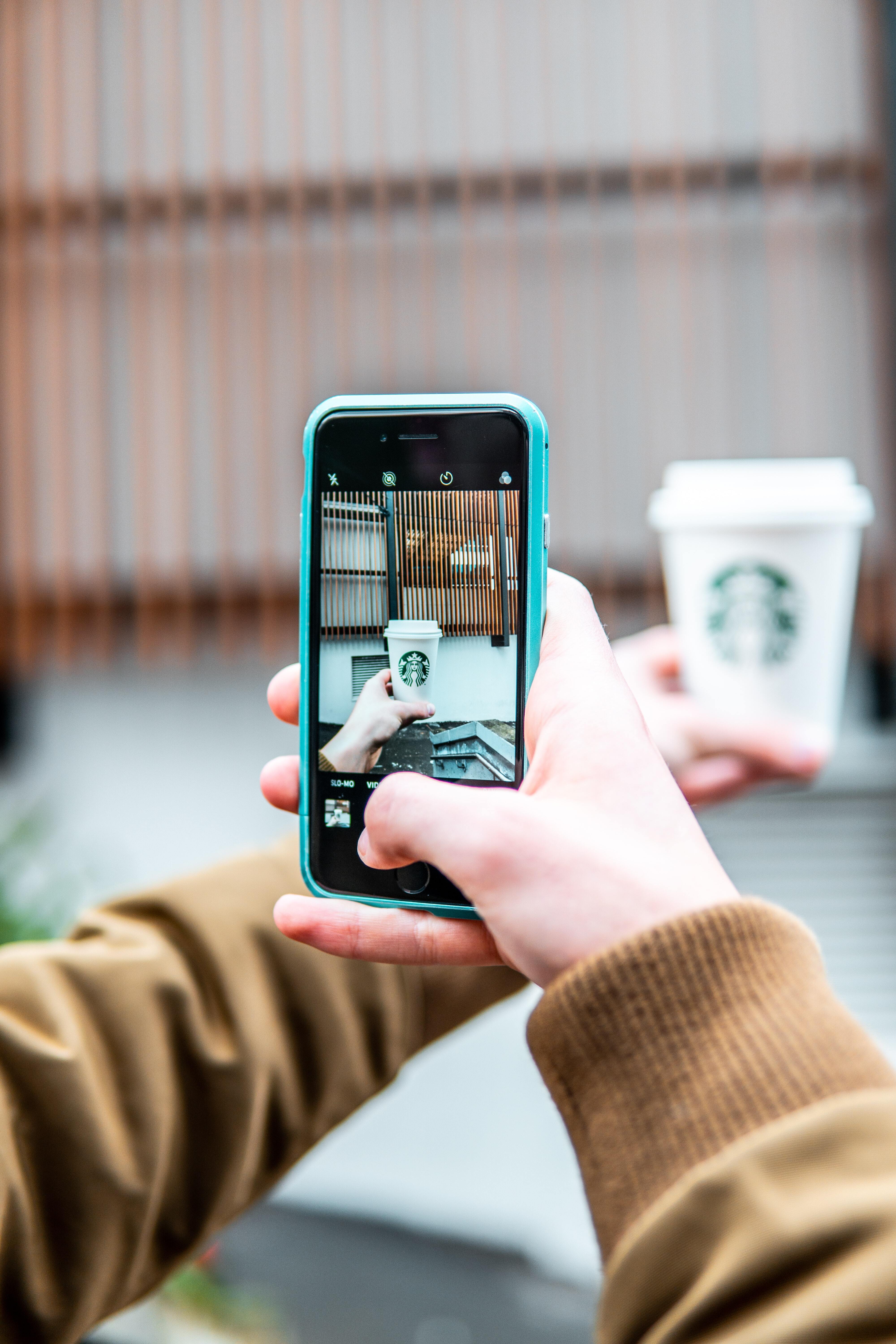 Person taking photo of Starbucks cup with smartphone